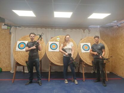 Three people standing in front of targets holding crossbows